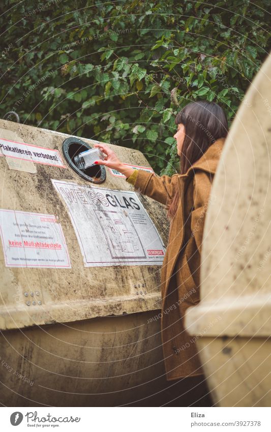 A young woman disposes of a bottle in a bottle bank. Recycling. Glass for recycling Container bottles Glass waste Trash Trash container waste separation