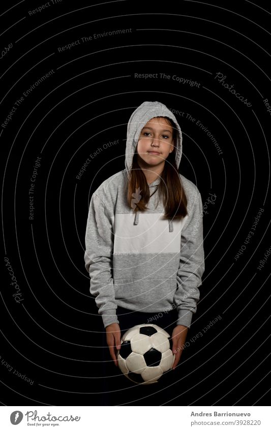 Little girl in gray sweatshirt and two pigtails playing with a soccer ball isolated on black background sport eye cut lifestyle joy beauty player young healthy