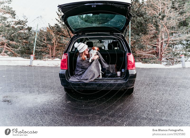 young woman and cute jack russel dog in car. Winter season, snowy mountain background blanket nature together wanderlust beauty active togetherness friends day