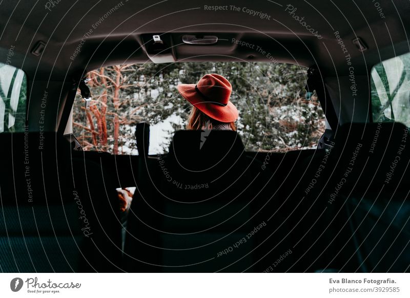 back view from inside a car of young woman outdoors wearing stylish hat. Winter season. snowy mountain background winter enjoy nature leisure green weather