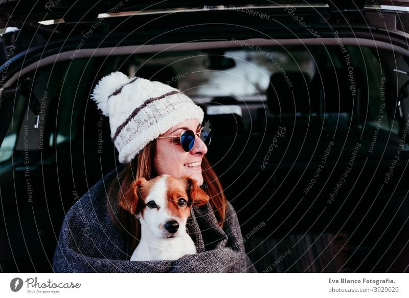 young woman and cute jack russel dog in car. Winter season, snowy mountain background blanket nature together wanderlust beauty active togetherness friends day