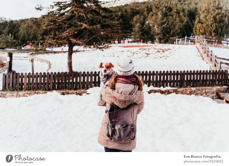 woman and cute jack russell dog enjoying outdoors at the mountain with snow. winter season holding shoulders love kiss hug travel lifestyle wanderlust traveling