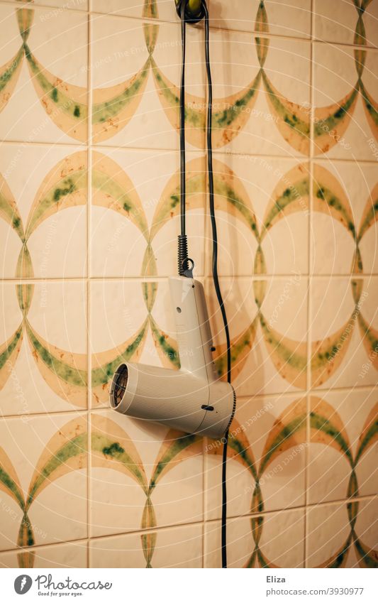 A hairdryer hangs on the wall in the retro bathroom Wall (building) Hang Retro 1970s variegated Old vintage Pattern Nostalgia tiles Old fashioned Past