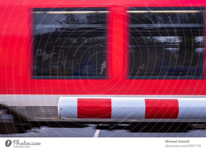 Train barrier closed and passing train Control barrier barrier tree Closed Wait waiting swift Track Transport Railroad Speed Movement Reddish white