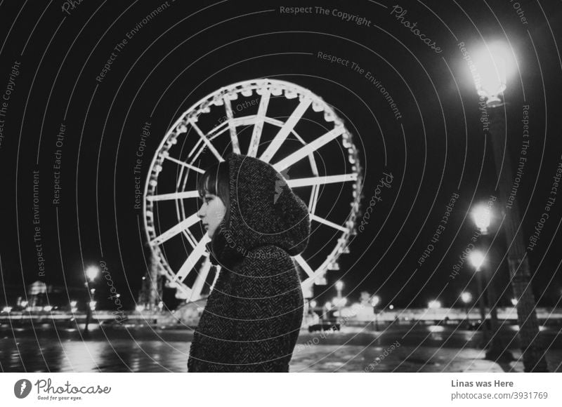 Paris at night is a beautiful thing. Even on such a cold autumn night. A pretty girl is wearing a coat and her profile aligns well with the Ferris wheel. The Black and white image is moody and nostalgic in a way. A lonely girl in an empty big city.