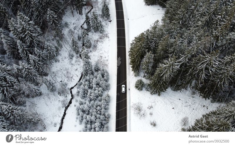 Aerial view with a drone of a road with a car driving through the forest in the winter time Aerial photograph drone photo Winter Street Driving Snow Forest