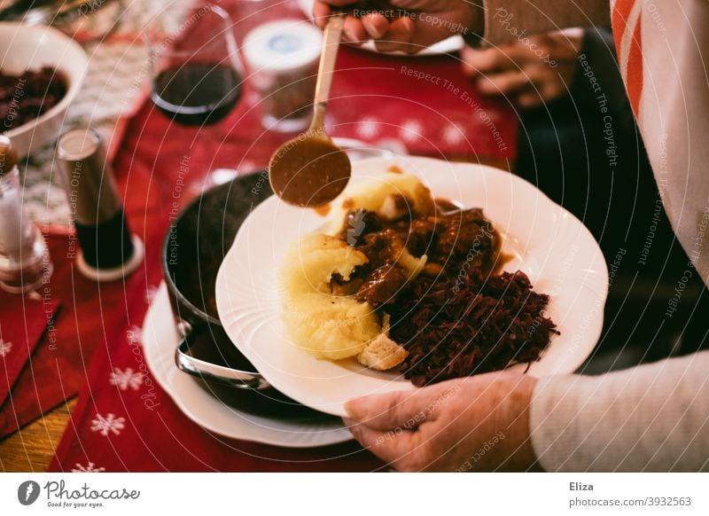 Grandma serves delicious food at the set table - venison goulash, dumplings and red cabbage. Eating Table hearty christmas dinner Goulash Dumpling Red cabbage