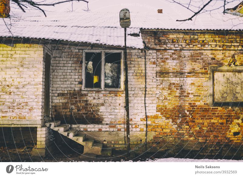 old brick building with concrete stairs, crooked roof covered with snow and old lantern Aged antique architecture background block brown construction décor