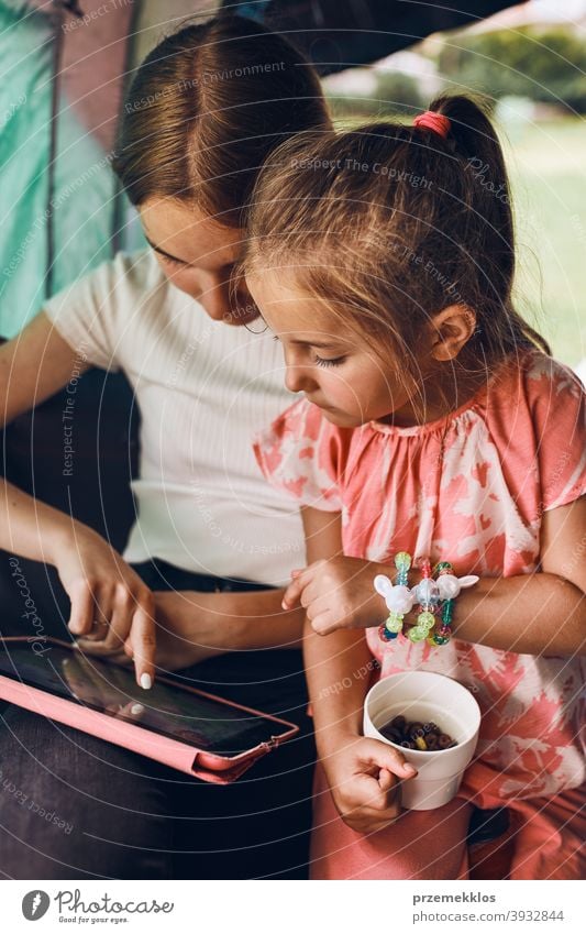 Sisters spending time in a tent on camping. Children using tablet playing games online during summer vacation children girl siblings sister family internet