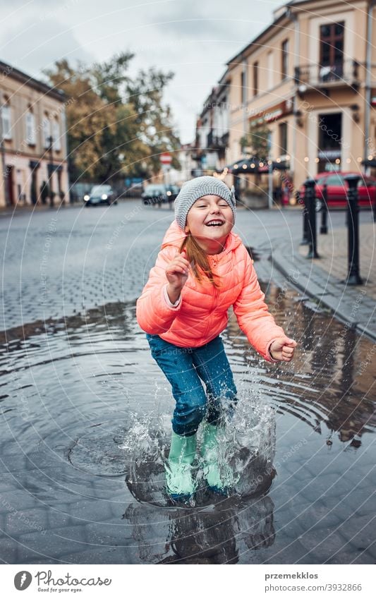 Little girl holding big umbrella jumping in the puddle on rainy gloomy autumn day raining outdoors little seasonal fall childhood beautiful weather outside kid