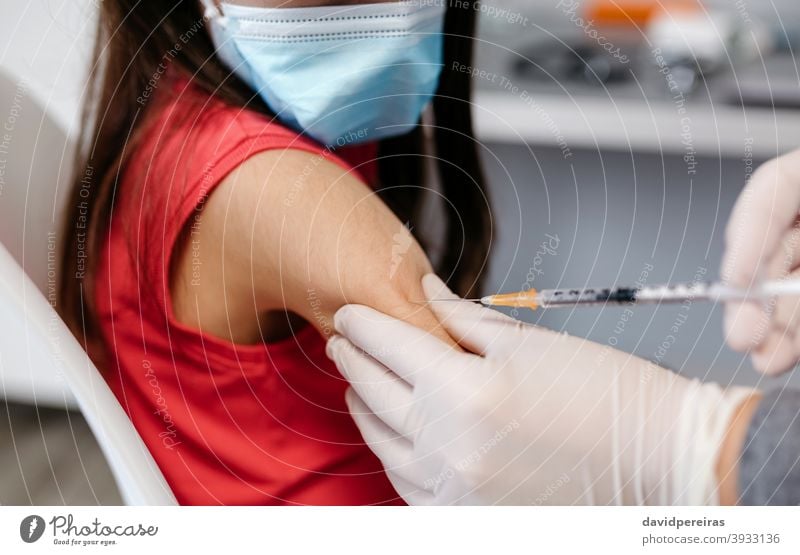 Closeup of girl receiving coronavirus vaccine at doctor's office injecting syringe little girl unrecognizable covid-19 detail closeup injection vaccination kid