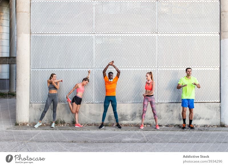 Diverse sportspeople warming up together in city stretch runner training warm up street company athlete workout diverse multiethnic multiracial black