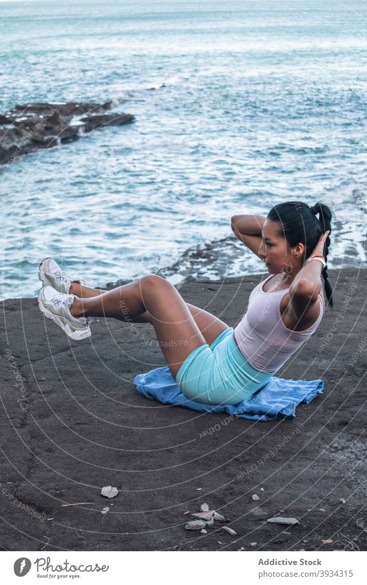 Athletic woman doing abdominal crunches during training at seaside abdomen abs workout balance exercise practice effort female beach vitality healthy