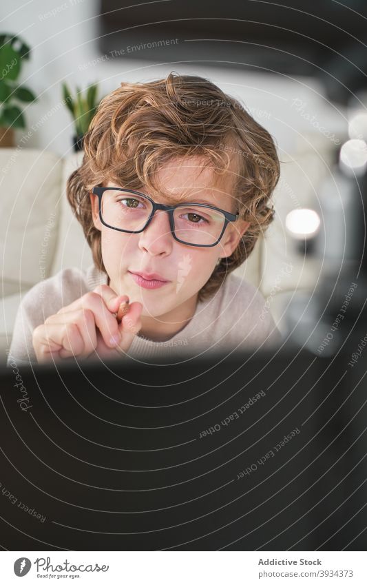 Happy Boy Recording Himself face front view camera portrait at home kid boy young boy youtuber couch technology equipment expressive expression fun online hobby