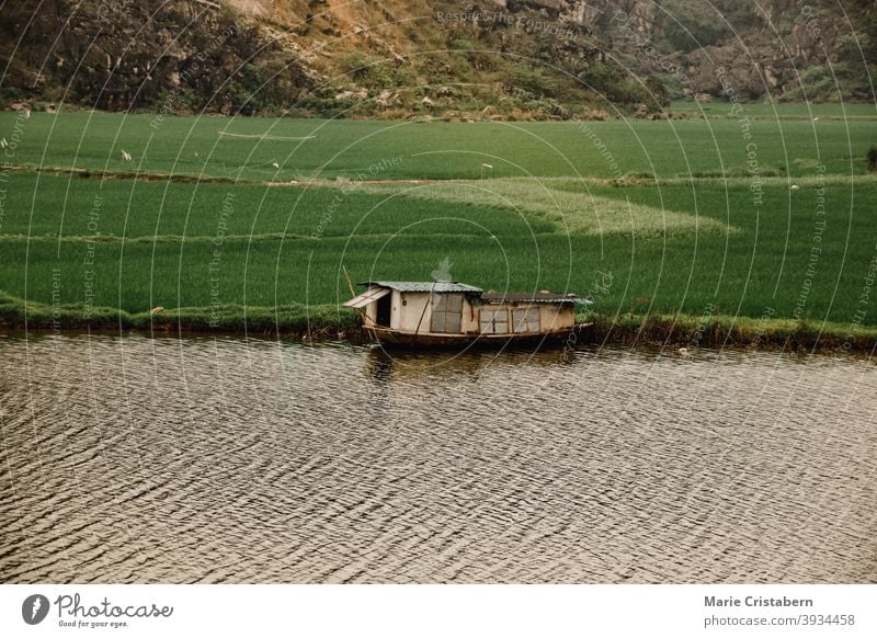 Cinematic scenery of a wooden boat house moored in the riverside of Ninh Binh, Vietnam cinematic rural scene agriculture rice field floating province tam coc