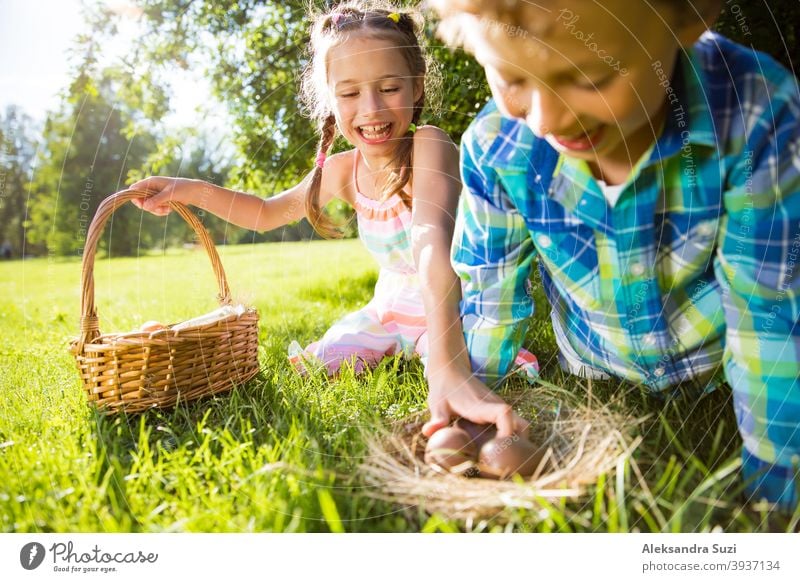 Cute boy and girl celebrating Easter, searching and eating chocolate eggs. Happy family holiday. Happy kids laughing, smiling and having fun. Beautiful spring sunny day in park