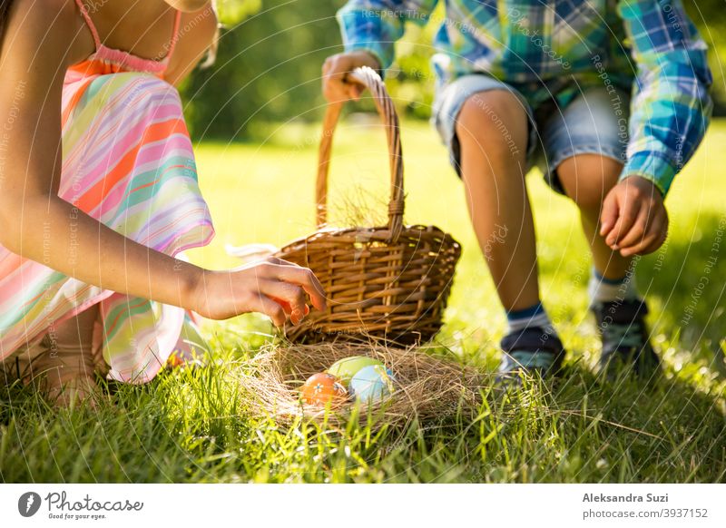 Cute boy and girl celebrating Easter, searching and eating chocolate eggs. Happy family holiday. Happy kids laughing, smiling and having fun. Beautiful spring sunny day in park