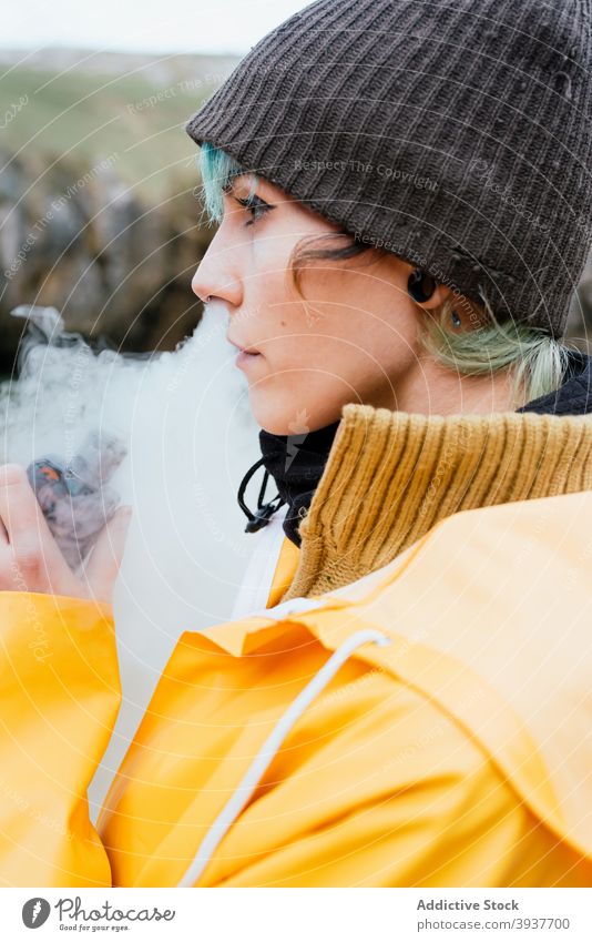 Woman smoking e cigarette in nature woman smoke vape electronic fume exhale smoker autumn outerwear female cobijero beach asturias spain rest nicotine tobacco