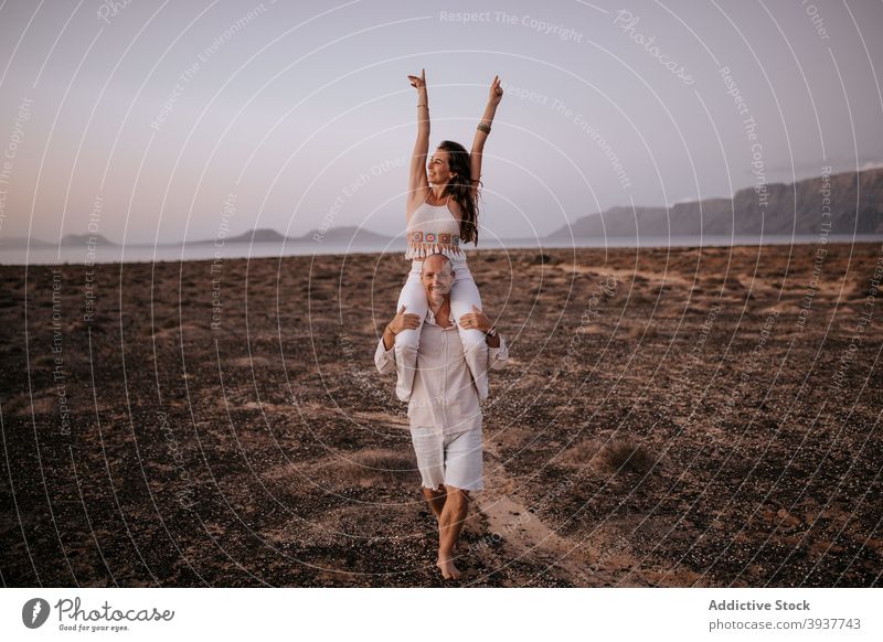 Carefree couple having fun in savanna in evening on shoulders ride nature cheerful carefree freedom barefoot together savannah walk joy relax happy smile sunset