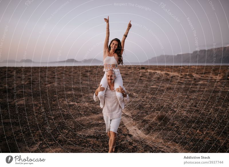 Carefree couple having fun in savanna in evening on shoulders ride nature cheerful carefree freedom barefoot together savannah walk joy relax happy smile sunset