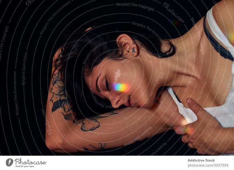 Tattooed woman lying on floor in studio serene tattoo dreamy relax peaceful charming harmony calm female eyes closed style unemotional slim pleasure emotionless