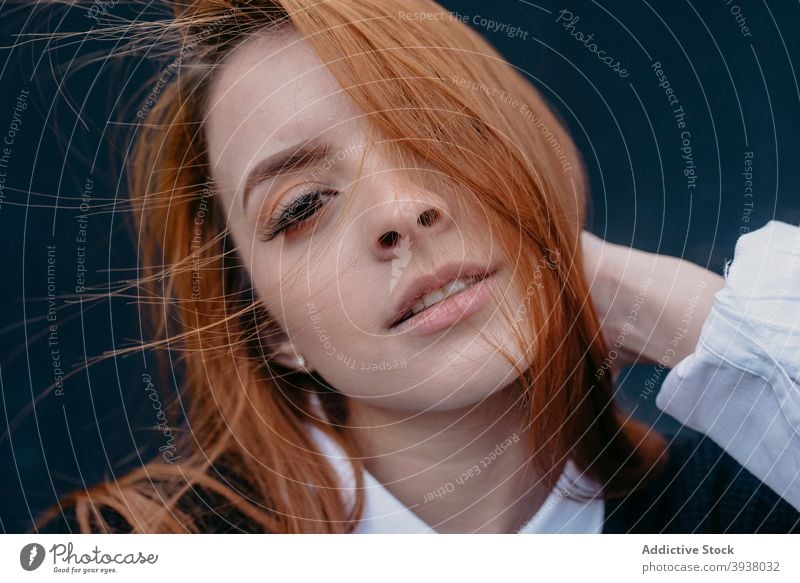 Smiling woman with wind in hair on street redhead flying hair carefree charming red hair enjoy smile female content young ginger cheerful city style positive