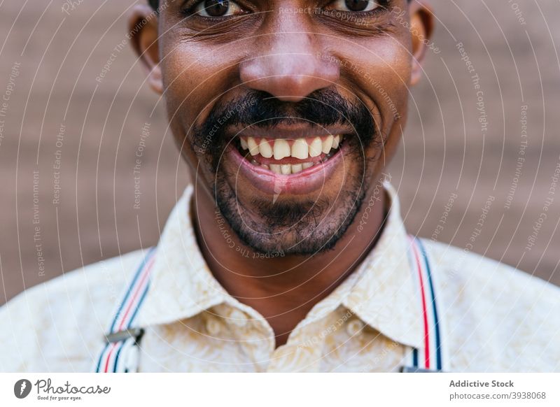 Happy stylish black man standing near building in city serene carefree street tranquil contemplate male ethnic african american curly hair rest afro urban