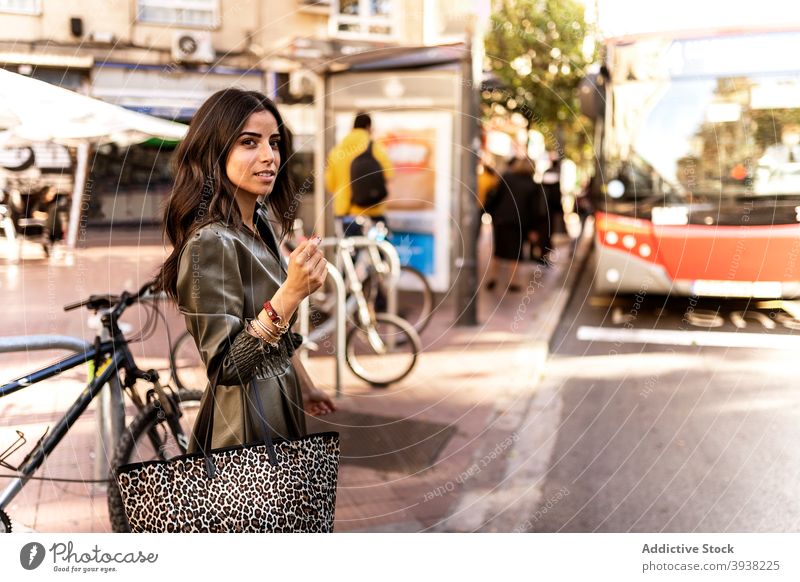 Gorgeous young lady walking on street after bus riding woman style confident public transport city sidewalk modern fashion female dark hair long hair dress