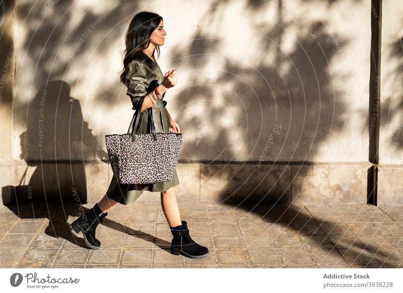 Self assured young ethnic woman strolling on street in sunlight walk positive style confident self assured pedestrian happy smile pavement city fashion female