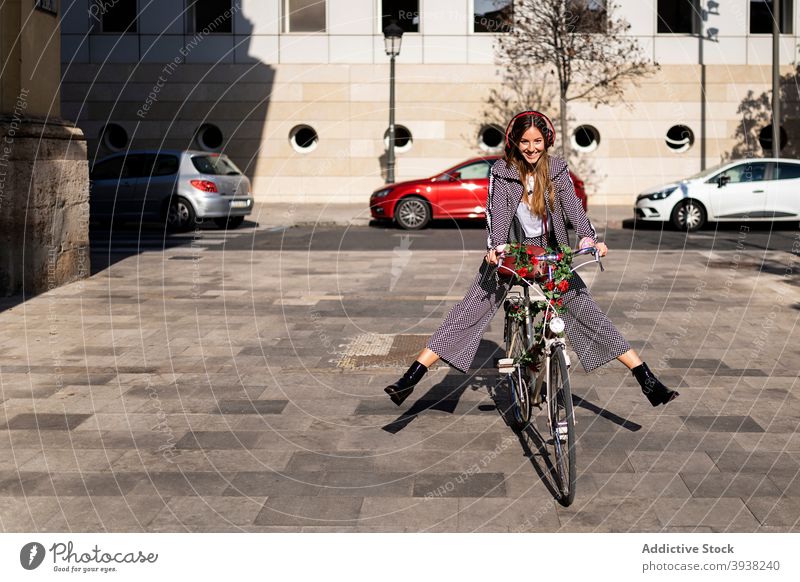 Cheerful woman riding bicycle on city street ride cheerful urban style having fun happy bike enjoy young female lifestyle trendy optimist positive excited