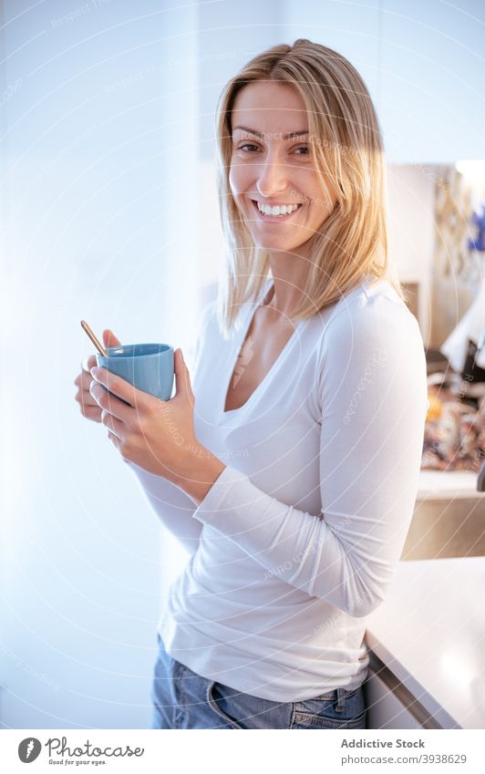 Woman drinking coffee in kitchen in sunny morning woman relax breakfast home energy caffeine interior furniture female young fit blond casual jeans modern cup