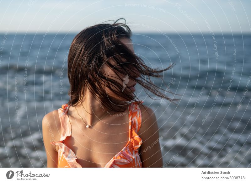 Pensive young ethnic woman relaxing on seacoast against cloudy sunset sky seashore vacation dreamy recreation nature traveler style holiday enjoy female