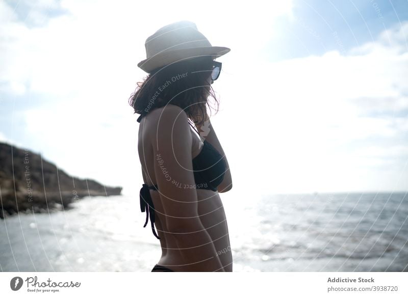 Pensive young ethnic woman relaxing on seacoast against cloudy sunset sky seashore vacation dreamy recreation nature traveler style holiday enjoy female