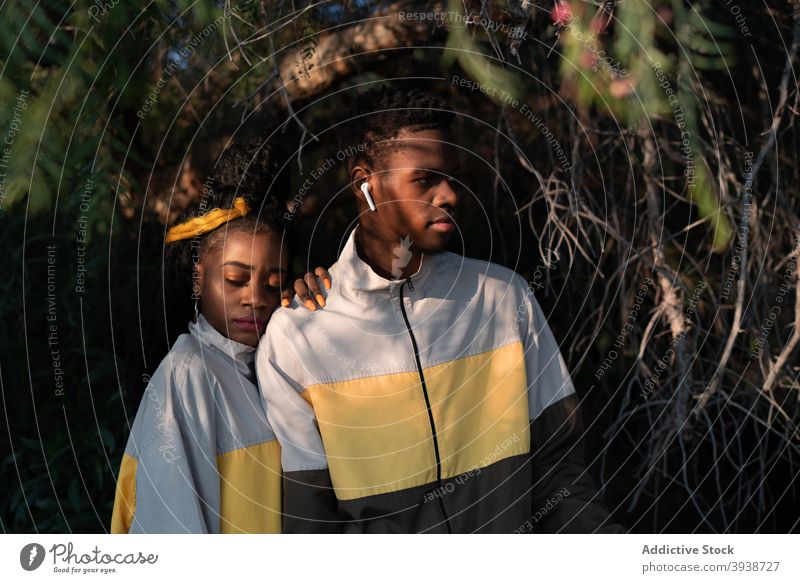 Stylish ethnic young couple hugging in park during romantic date cuddle calm love affection tender spend time relax amorous boyfriend girlfriend black