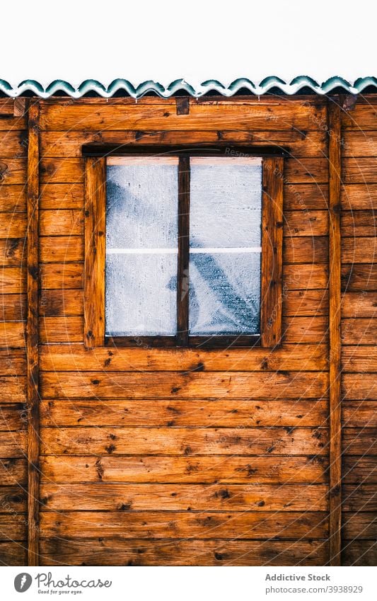 Old wooden cottage with snowy roof and frozen window house hoarfrost winter forest exterior cold hut village countryside nature calm peaceful residential