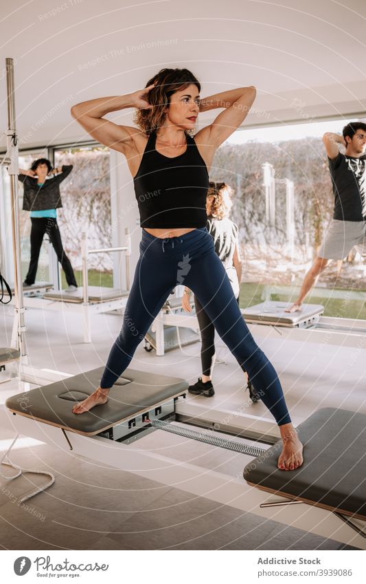 Group of people doing exercises on pilates reformer class group training machine workout healthy together wellbeing physical sportswear energy fit activity