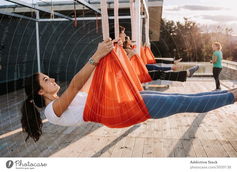 Women doing yoga in hammocks on terrace class group women practice hang asana pose flexible female activewear sunny together healthy balance zen energy