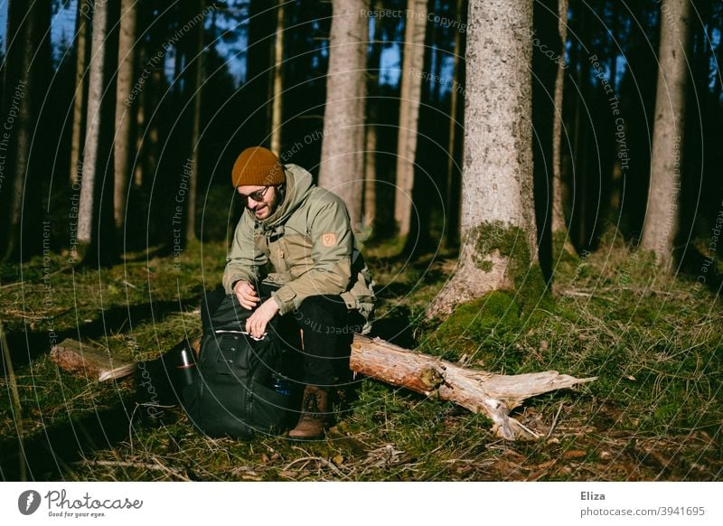 A man sits in the forest on a tree trunk in the sun Man Trip Forest Tree trunk Sit trees Nature Break sunshine Sun Winter Autumn close to nature Exterior shot