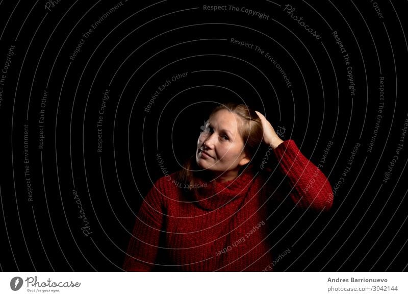 Pretty woman in a red woolen sweater posing smiling on black studio background. Copy space cute one girl agreement gesture happy casual closeup pretty portrait