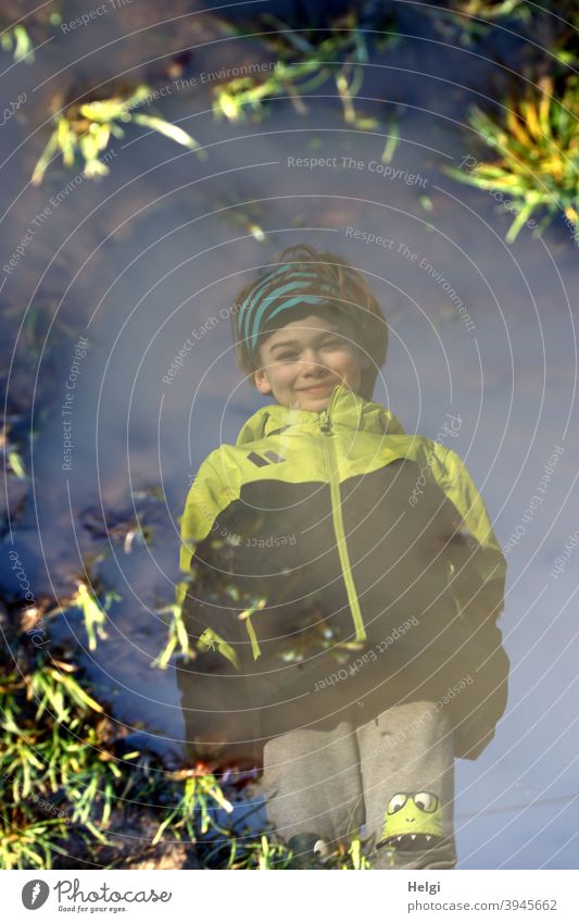 surreal - portrait of a boy in black and yellow jacket and grey trousers reflected in a puddle on a dirt road Human being Child Boy (child) Puddle reflection