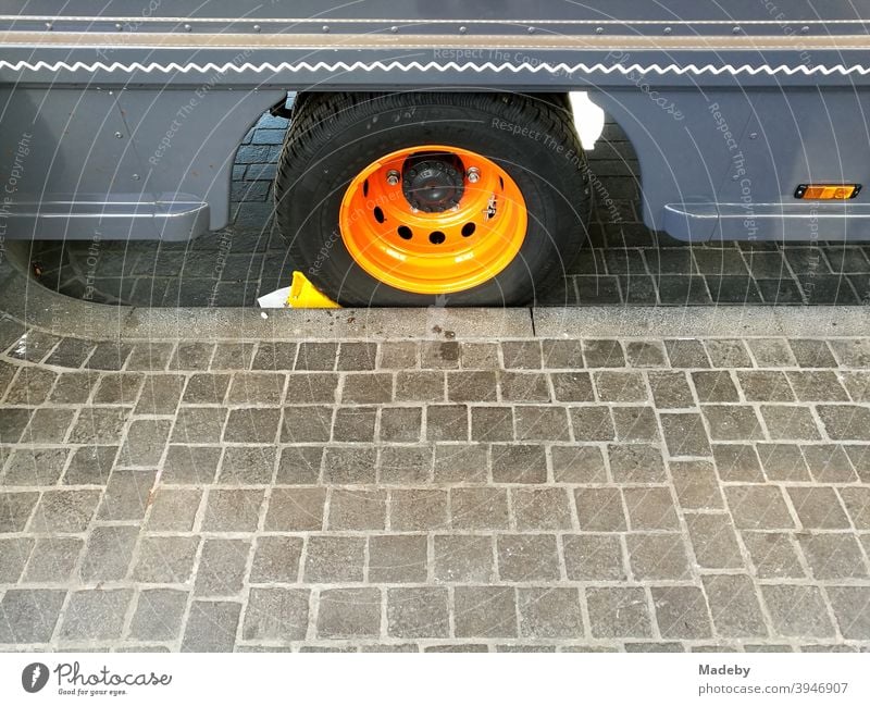 Food truck in blue with rim in bright orange at the curb of a paved sidewalk foodtruck food truck Wheel rim Blue Orange Imniss off Sidewalk Stripe decoration