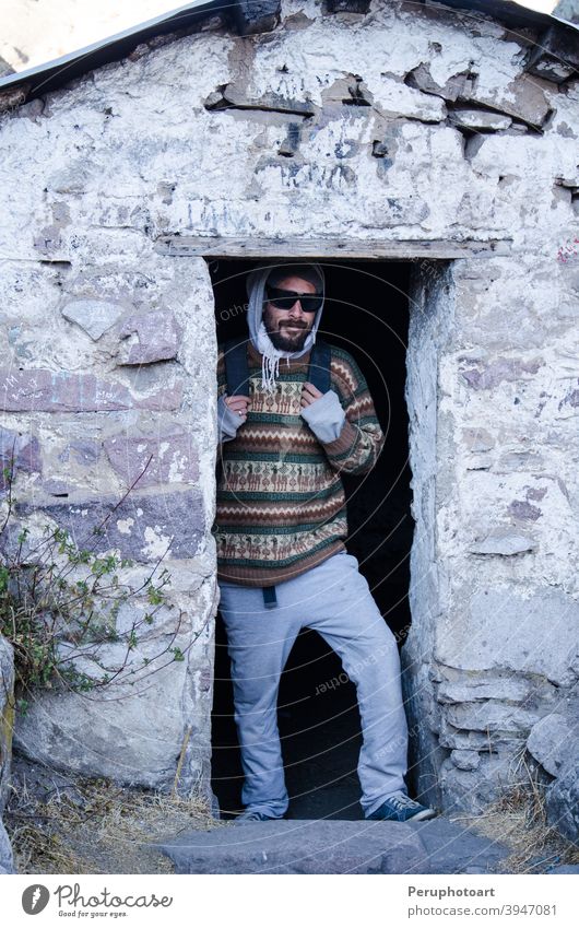 Traveling man with glasses poses in front of Daniel Russo's house in Marcahuasi Mountain travel Adventure Climbing Success Man height Extreme Nature Rock Sports