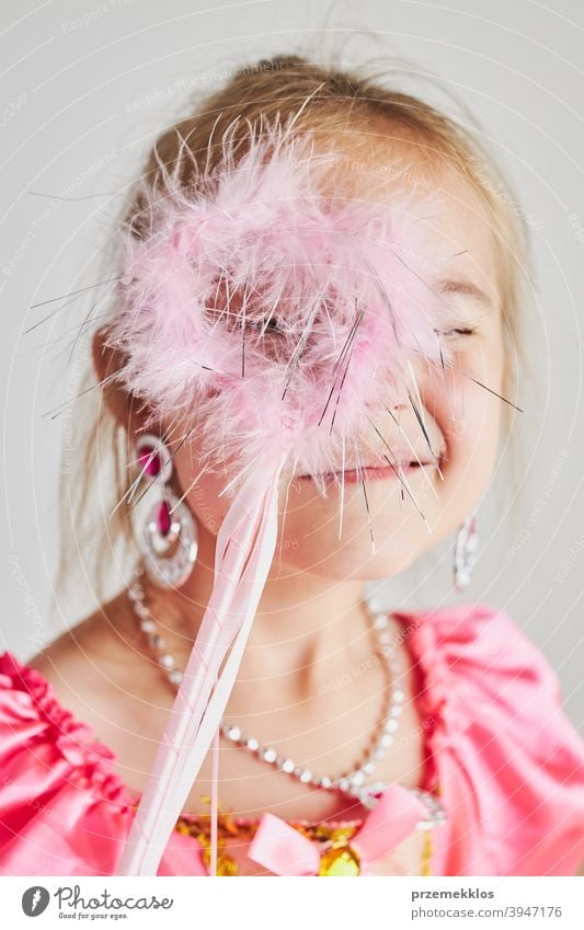 Little girl enjoying her role of princess. Adorable cute 5-6 years old girl wearing pink princess dress holding magic wand fairy child festival lifestyle joyful