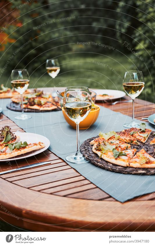 Dinner in a home garden. Pizza, salads, fruits and white wine on table in a backyard beverage celebration dinner dish drink eating feast food gathering having