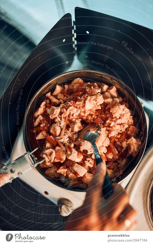 Close up of female hands putting dish with tomato sauce. Woman cooking meal on electric stove on camping during summer vacations cooker cuisine dinner eating