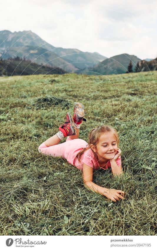 Little girl laying playing on grass enjoying summer day during vacation trip happy excitement enjoyment leisure emotion positive lying lifestyle activity