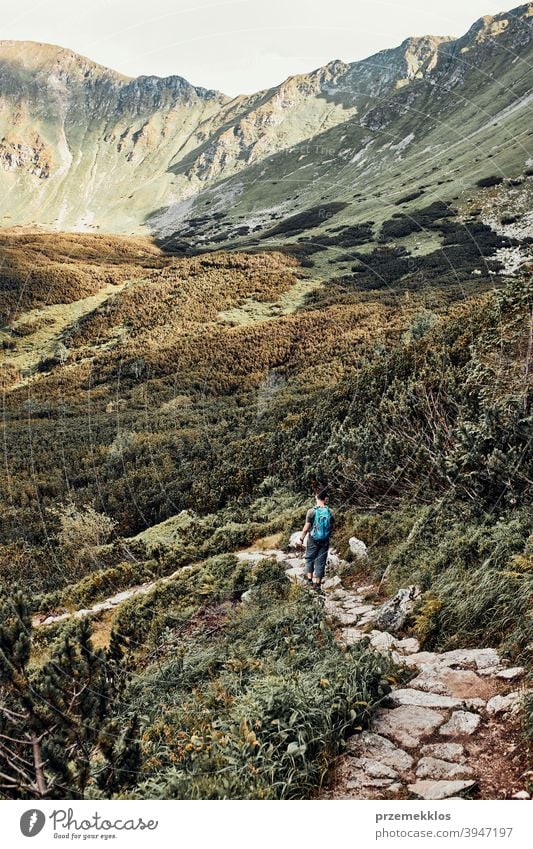 Young man with backpack hiking in a mountains, actively spending summer vacation activity adventure freedom healthy joy leisure nature park recreation spring