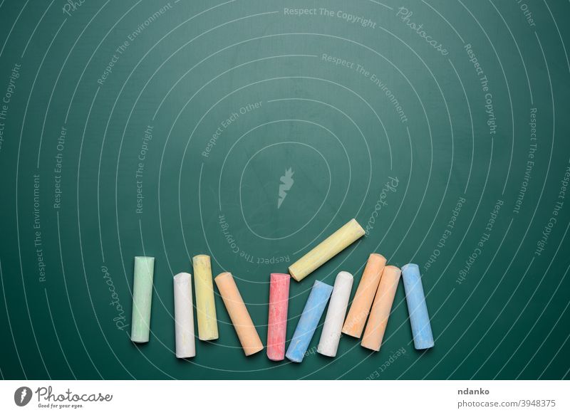 multicolored crayons on the background of green chalk school blackboard ad empty frame handwriting learning message nobody piece stick study surface wall white