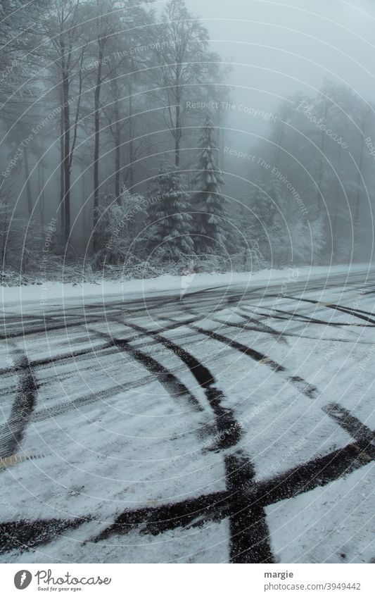 a wintry forest with tire tracks on a slippery road with snow and ice Winter Black ice ice and snow Ice and frost Tracks Skid marks trees Nature Landscape