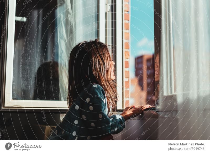 Beautiful shot of a little girl with dark hair looking out the window on a sunny day. Sun Sunlight Portrait Child Girl Childhood portrait child kid cute Infancy